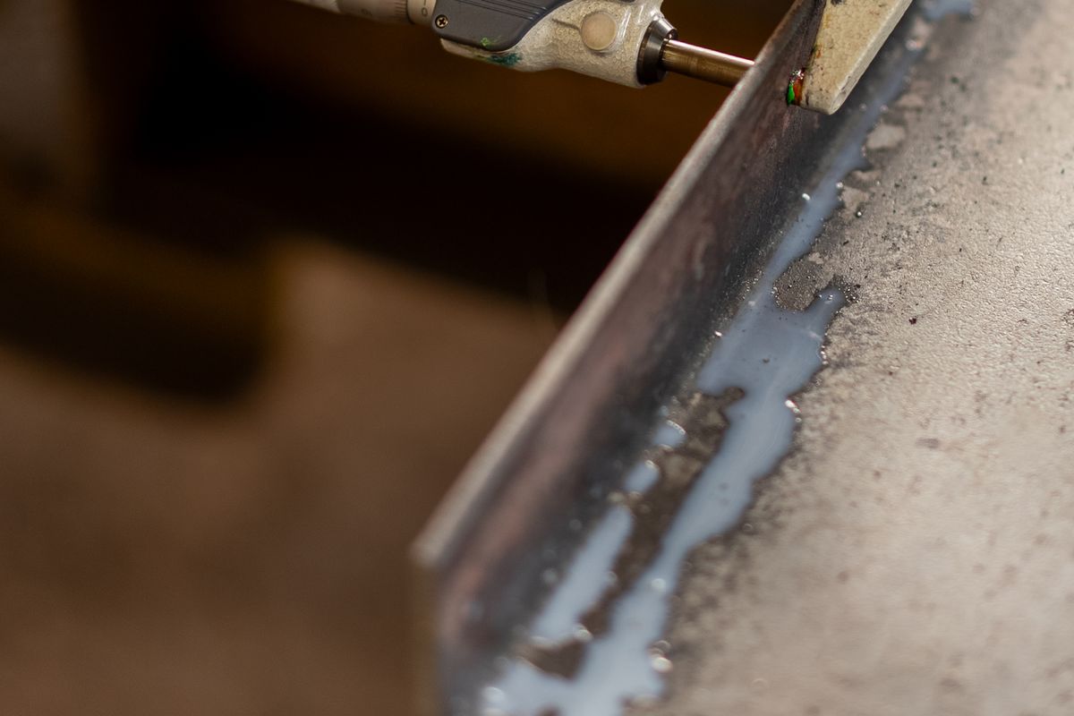 Micrometer taking a precision thickness reading on a steel component